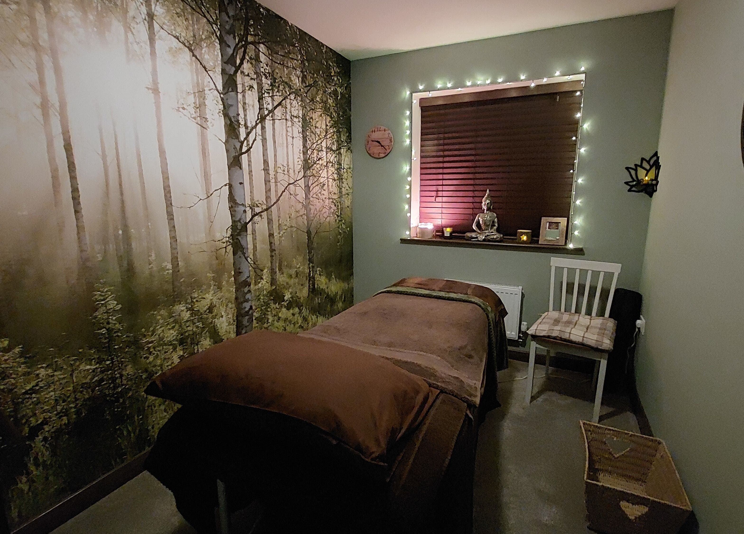 Tranquil spa room at Forest Massage Therapies, Saint Helens, featuring forest mural and soft lighting.