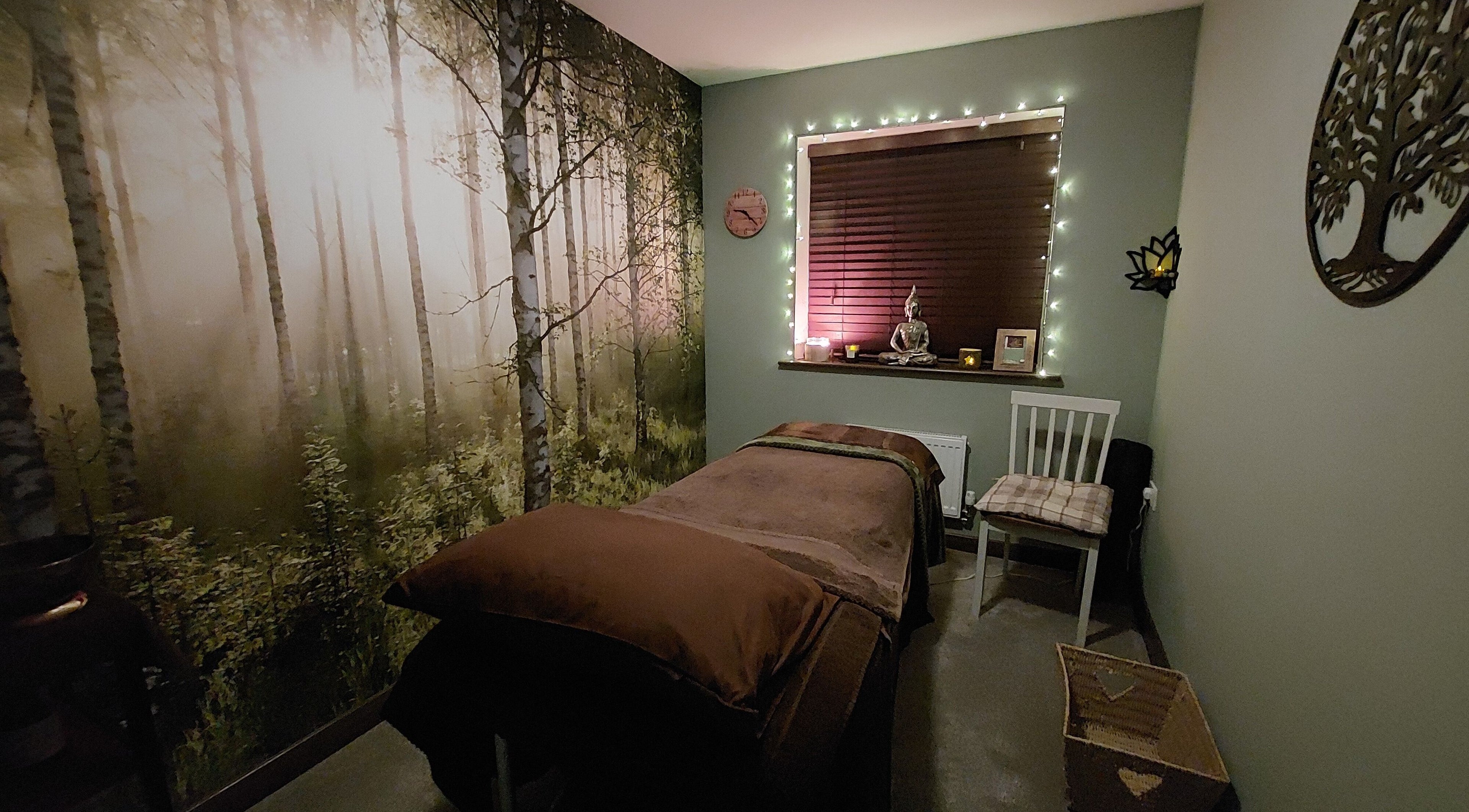 Tranquil spa room at Forest Massage Therapies, Saint Helens, featuring forest mural and soft lighting.
