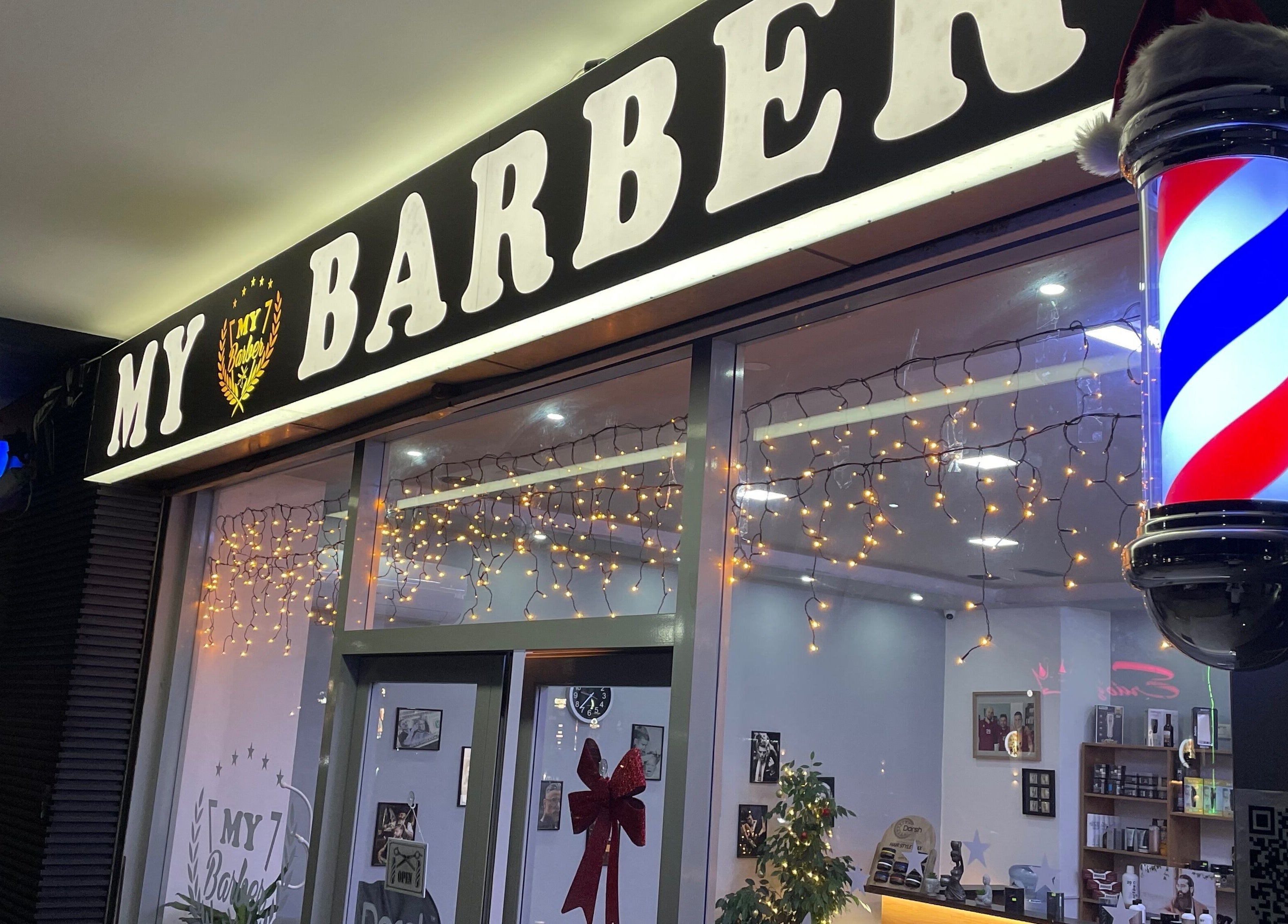 Glowing Barbershop sign with holiday decor in Durrës, Qarku I Durrësit, AL, inviting customers.