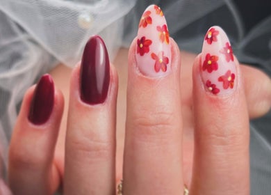 Manucure florale élégante chez Stella Nails à Bacilly, Normandie, FR, avec motifs rouges et base rose.