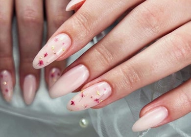 Mains avec ongles en gel rose et paillettes chez Stella Nails, Bacilly, Normandie, FR.