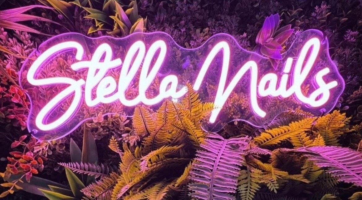 Enseigne néon de Stella Nails entourée de plantes, Bacilly, Normandie, FR.