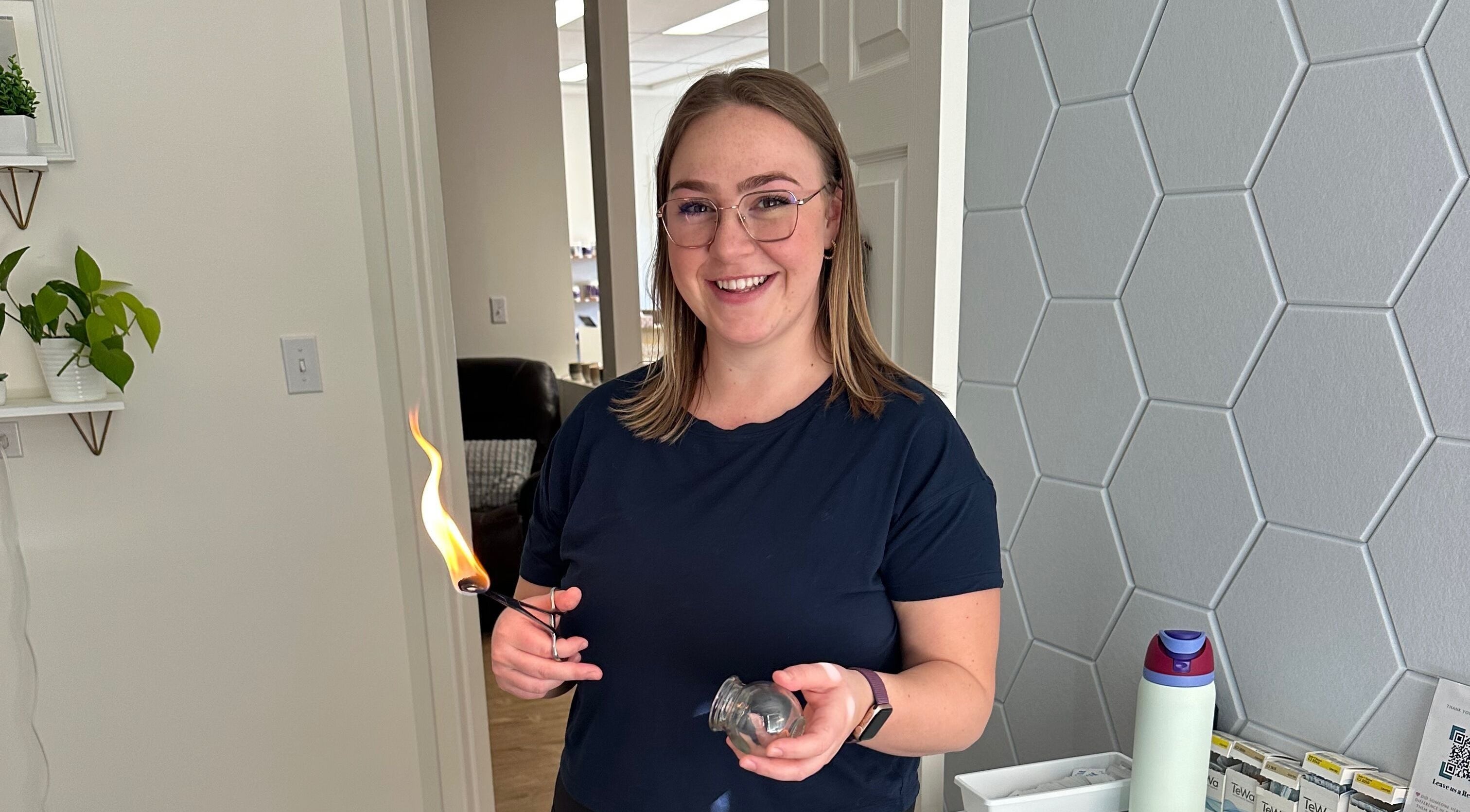 Therapist at Capture Relaxation in Paradise Hill, SK, CA, holding a cupping jar with flame.