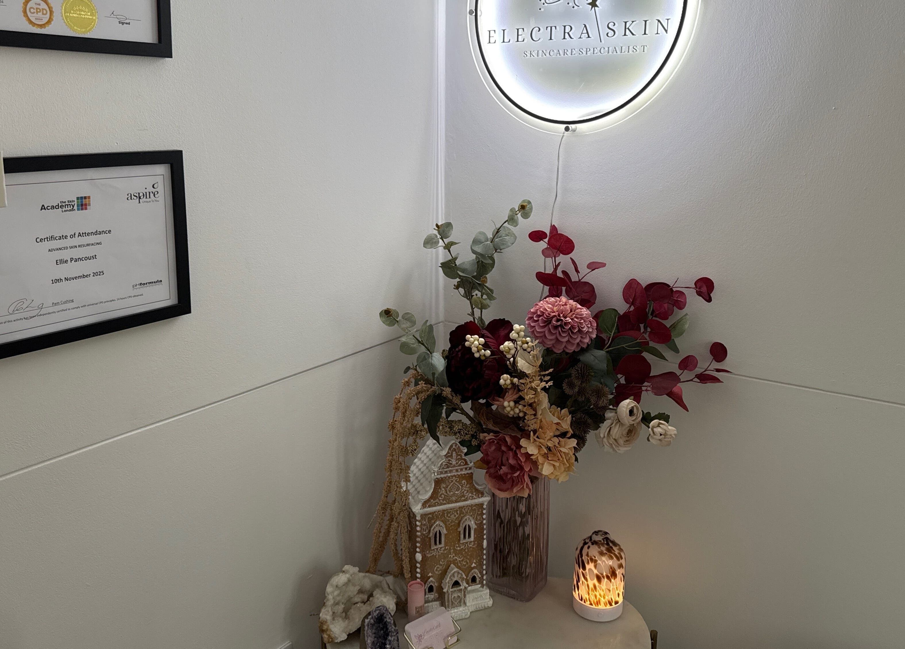 Cozy decor with certificates at Electra Skin, Upton, England, GB, glowing ambiance with flowers and light.