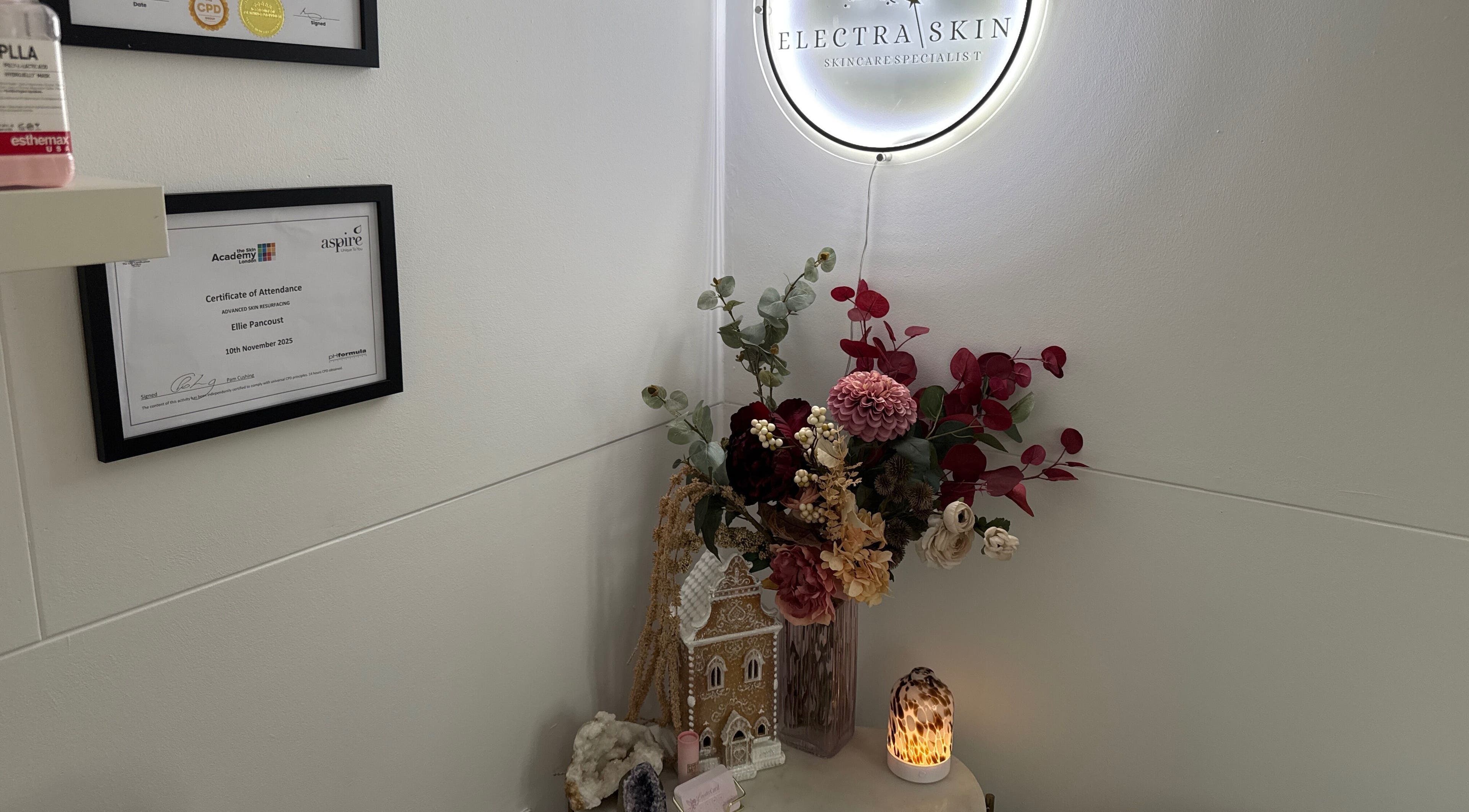 Cozy decor with certificates at Electra Skin, Upton, England, GB, glowing ambiance with flowers and light.