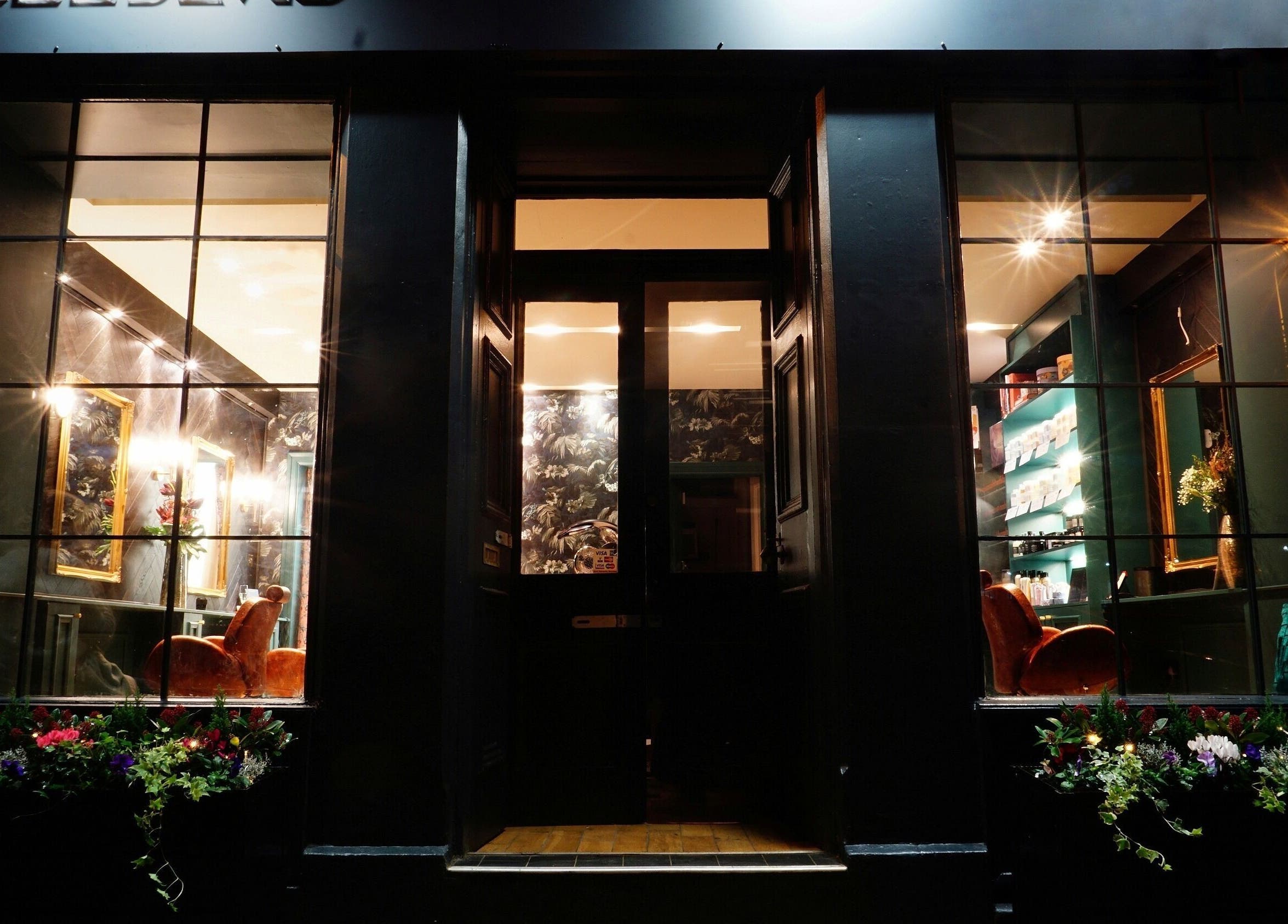 Warm evening view of Hair Gal Jaz, a stylish salon in Edinburgh, Scotland, GB, with inviting interior lighting.