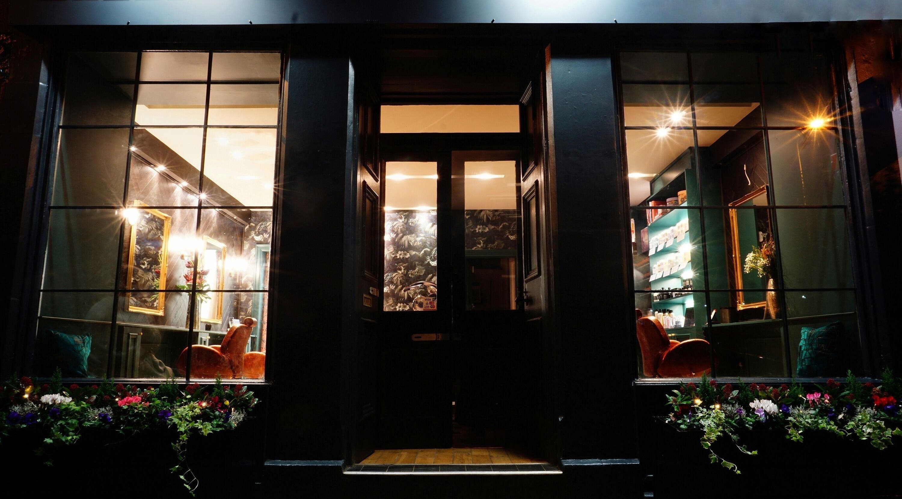 Warm evening view of Hair Gal Jaz, a stylish salon in Edinburgh, Scotland, GB, with inviting interior lighting.