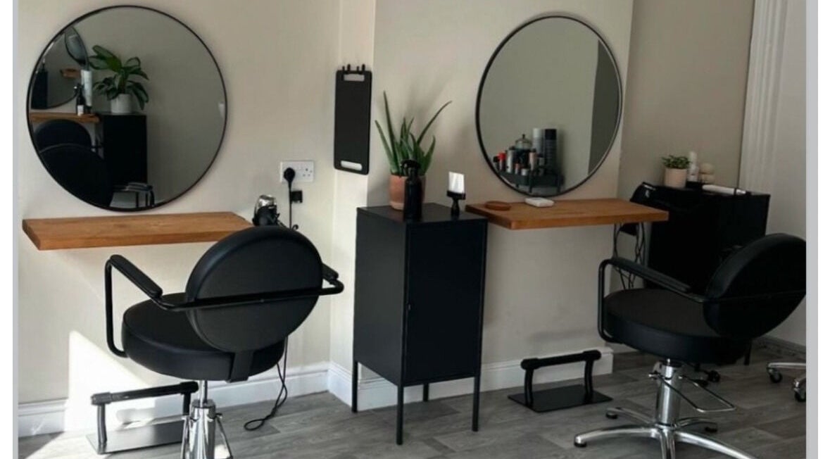 Modern hair styling stations at Izzy Ferguson hair in Ilkeston, England, GB with round mirrors and black chairs.