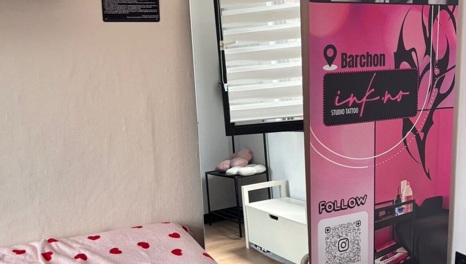 Coin confortable du Ink.No à Blégny, Région Wallonne, BE, avec bannière rose et lit à cœurs rouges.