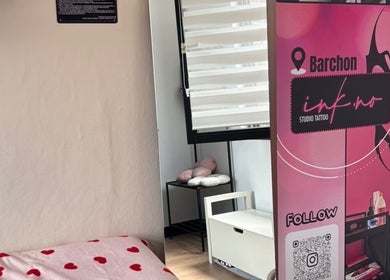 Coin confortable du Ink.No à Blégny, Région Wallonne, BE, avec bannière rose et lit à cœurs rouges.