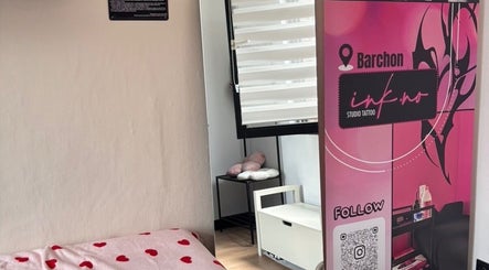 Coin confortable du Ink.No à Blégny, Région Wallonne, BE, avec bannière rose et lit à cœurs rouges.