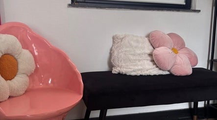 Fauteuil rose en forme de pétale chez Ink.No, Blégny, Région Wallonne, BE avec coussins fleuris.