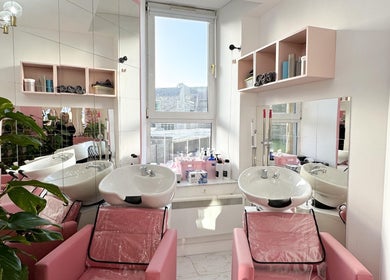 Modern hair washing area at Aberdeen Millmo salon in Aberdeen, Scotland, GB with pink chairs and plants.