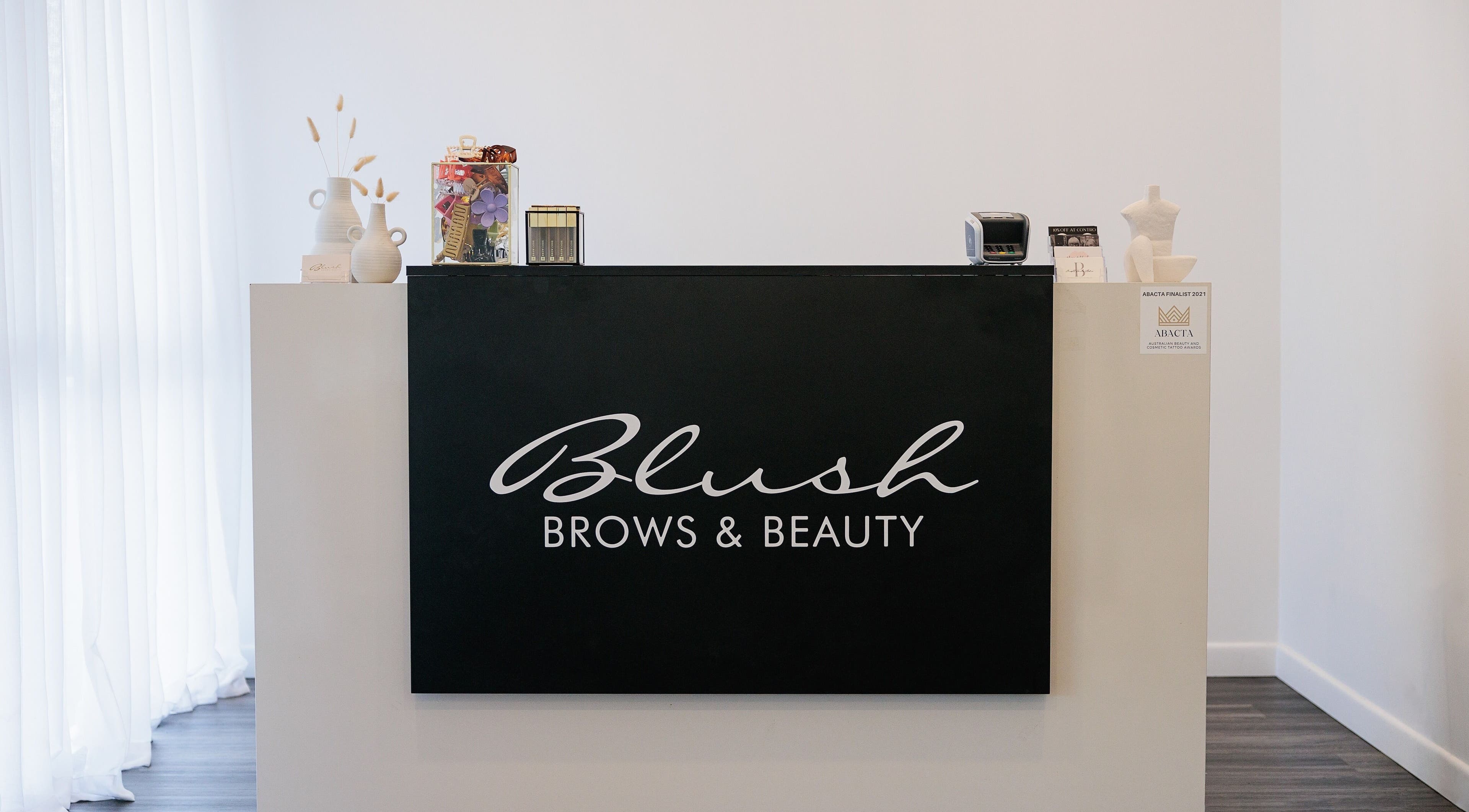 Reception desk at Blush Brows + Beauty in North Mackay, Queensland, AU with elegant decor and branding.