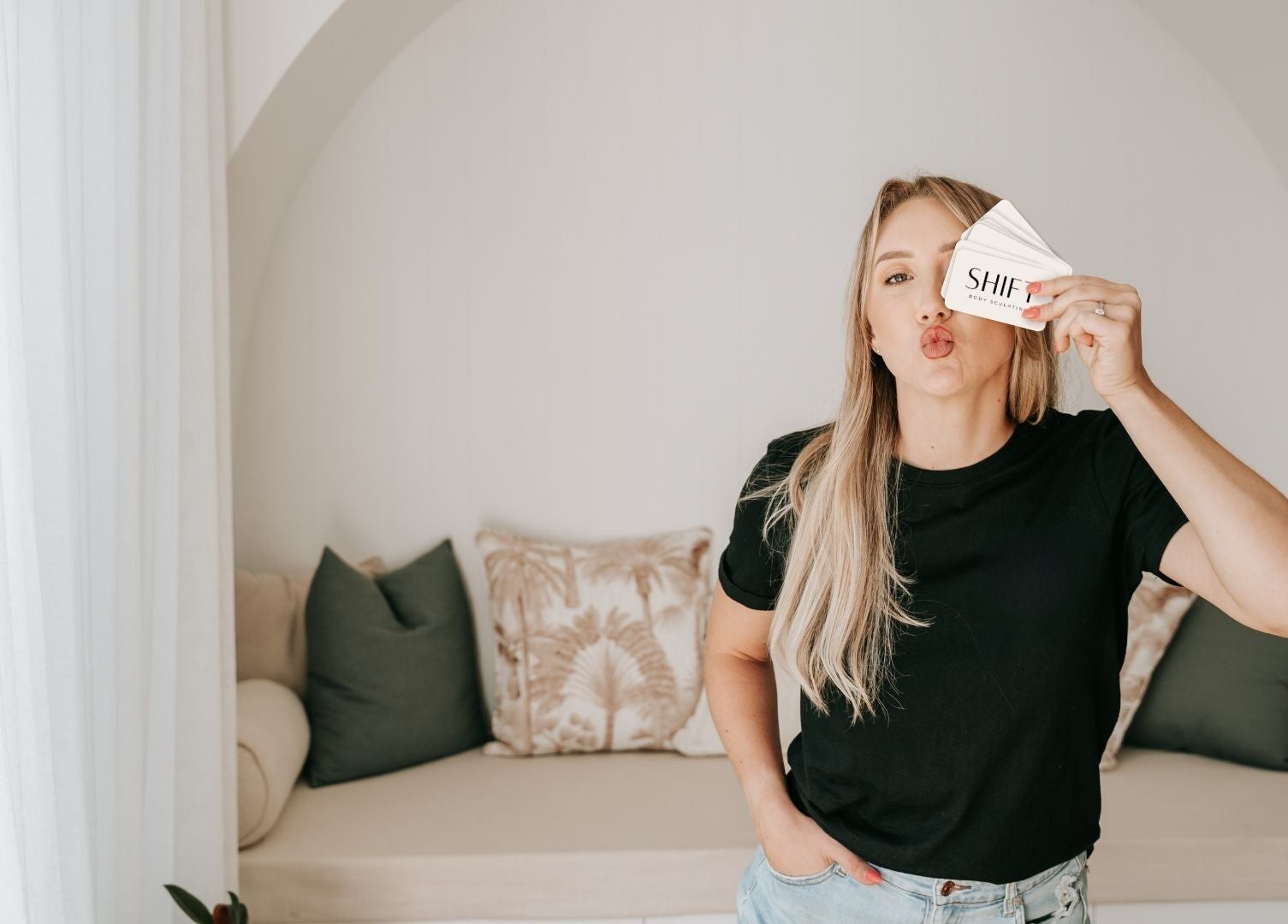 Woman holding SHIFT Body Sculpting card in cozy space, Waikiki, Western Australia, AU.
