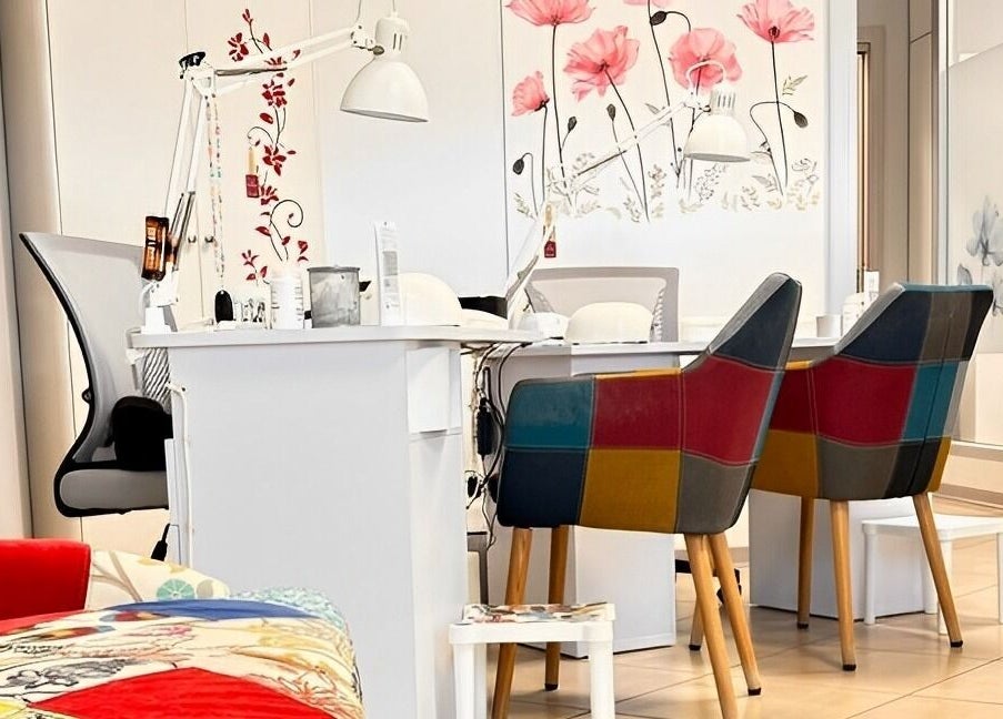 Interno di Manimania Estetica e Benessere a Travagliato, Lombardia, IT, con sedie colorate e tavolo per trattamenti.