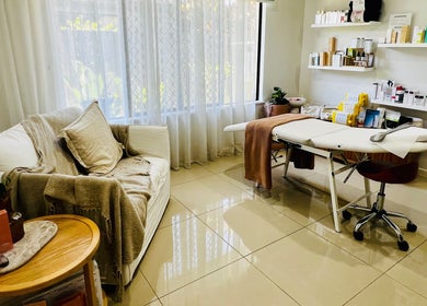Cozy treatment room at Healthy Skin Lab, Trinity Beach, Queensland, AU with sofa, massage table, and skincare products.