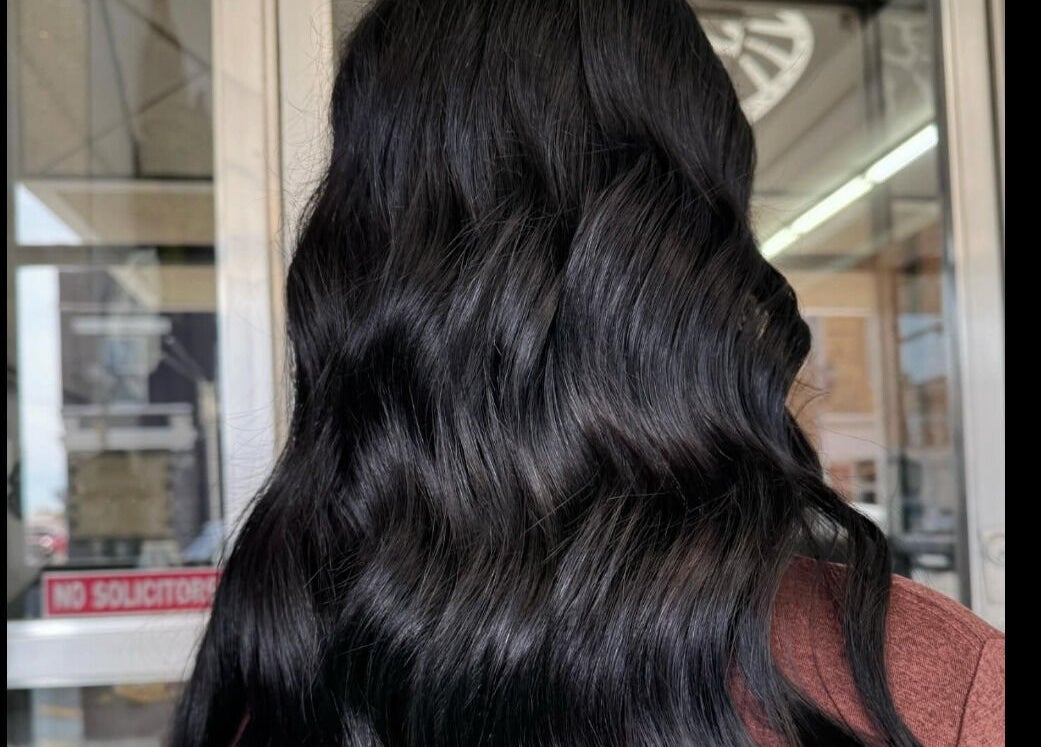 Sleek black hair styled in waves at Emmah, Transcendence Salon & Spa, Columbus, Nebraska, US.