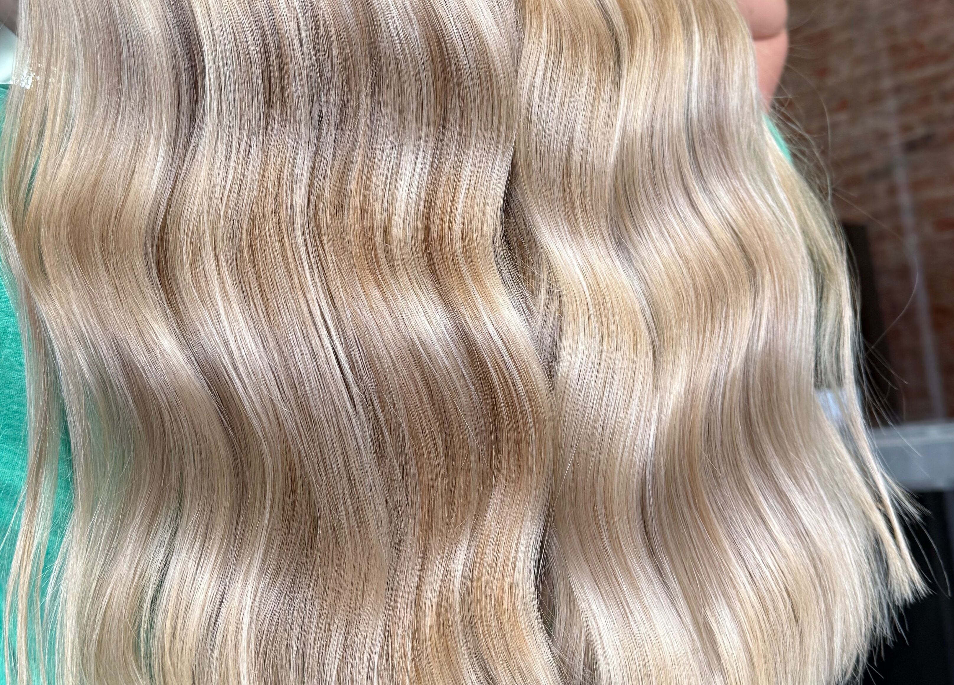 Shiny, wavy blonde hair styled at Emmah at Transcendence Salon & Spa, Columbus, Nebraska, US.