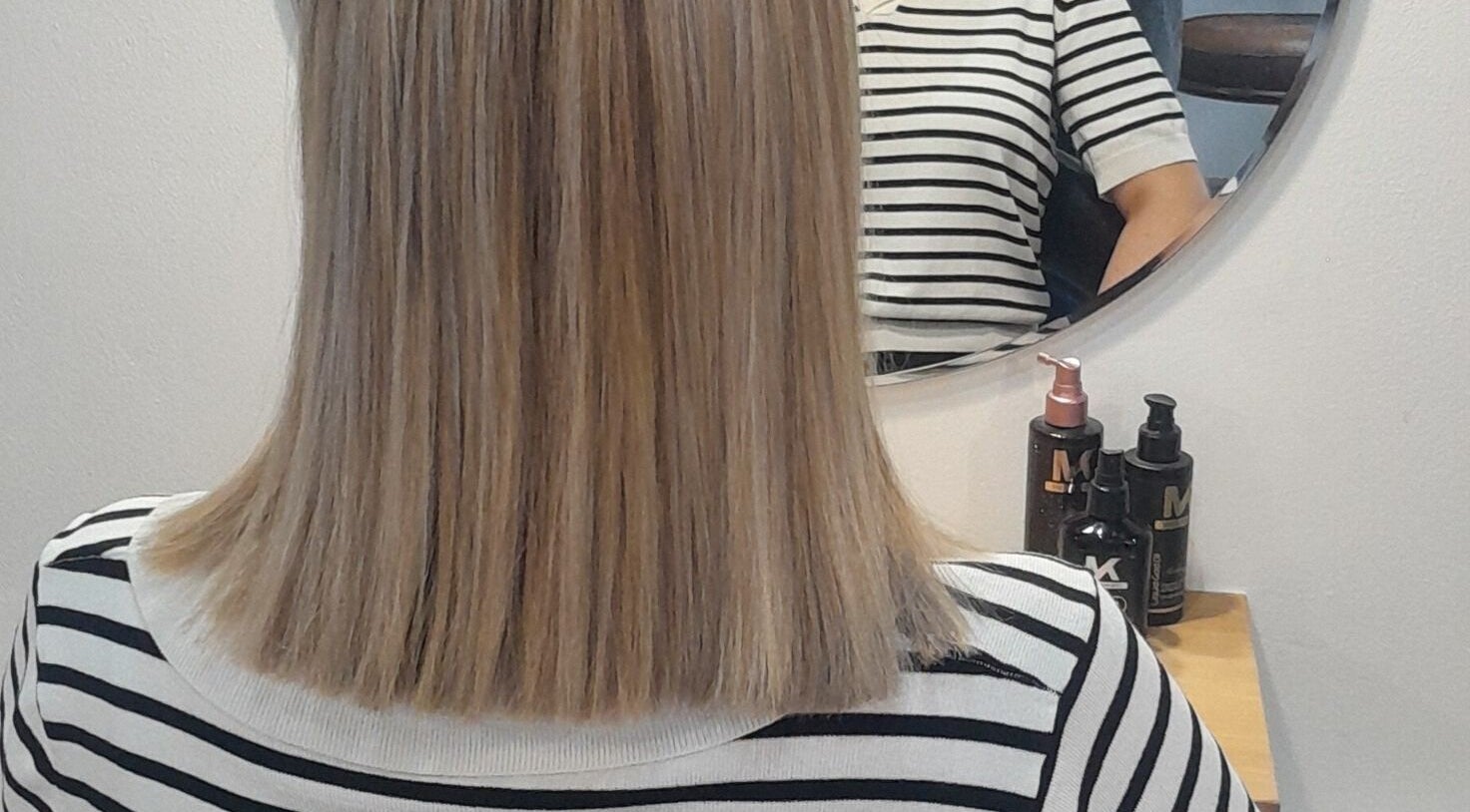 Straight hair styled at HAIR BY LILI, Pretoria, Gauteng, ZA, reflected in mirror with styling products visible.