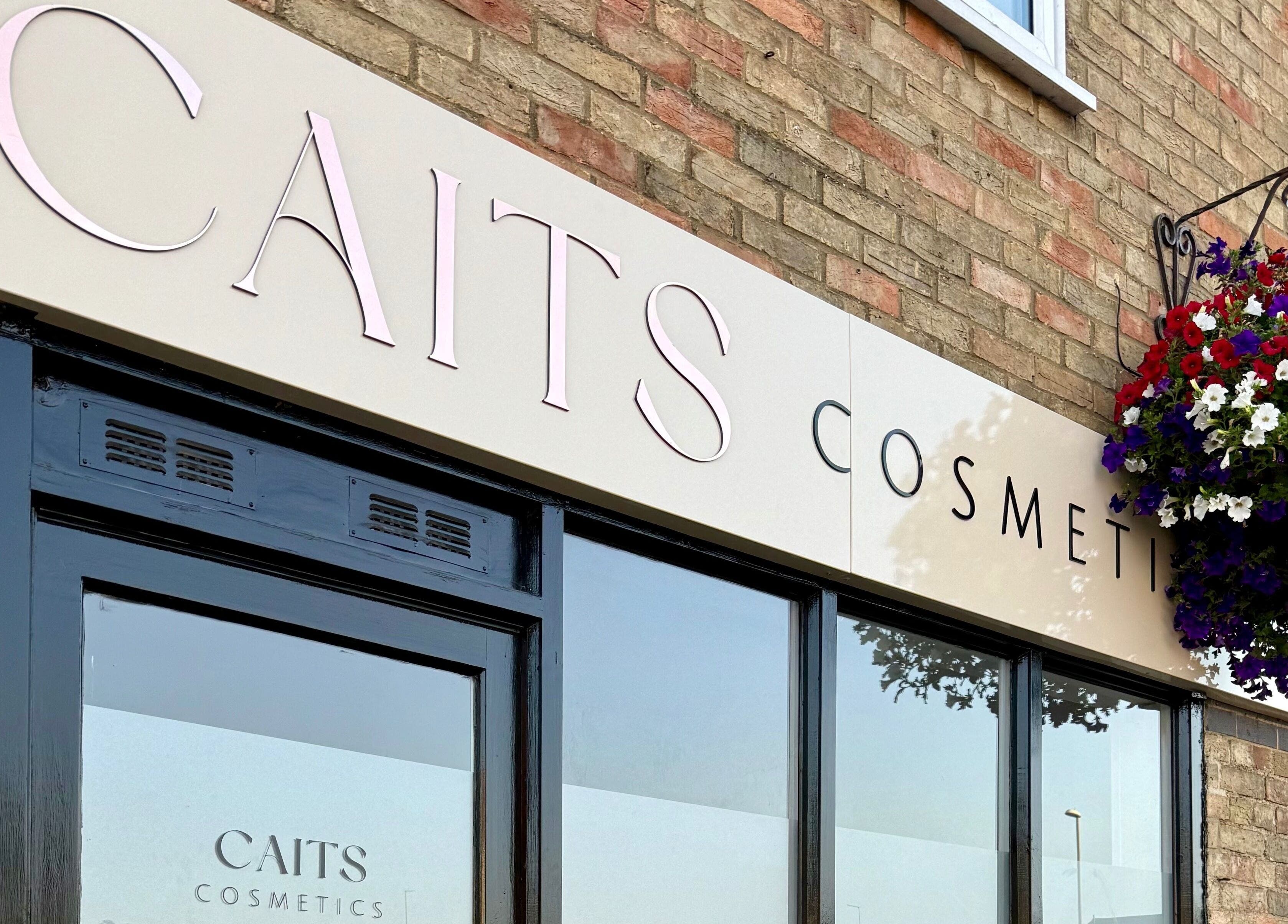 Entrance of Caits Cosmetics in Whittlesey, England, adorned with a vibrant floral display.