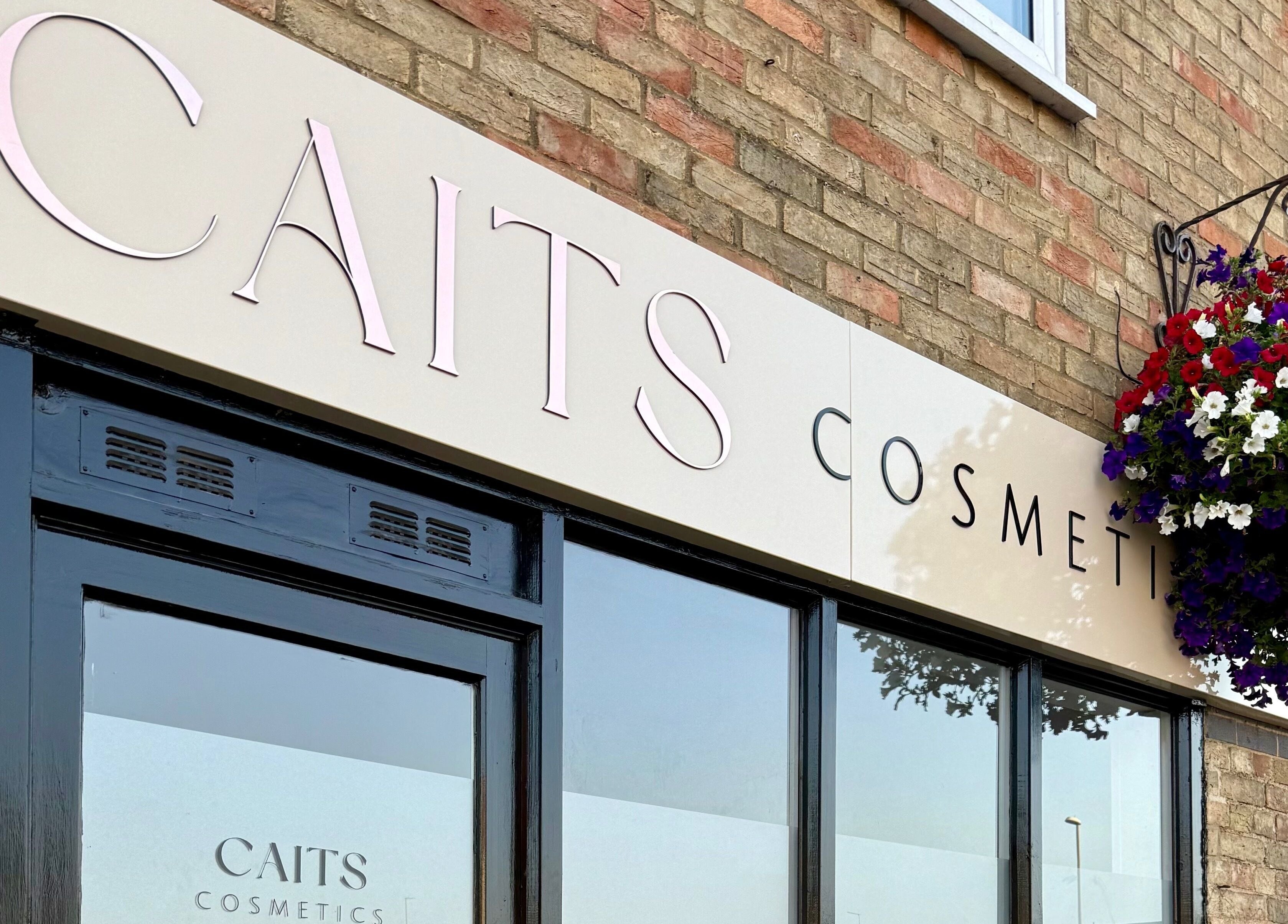 Front of Caits Cosmetics, Whittlesey, England, GB with elegant signage and hanging floral decor.