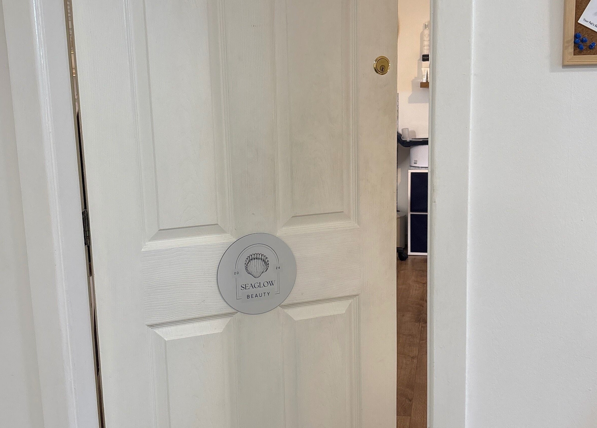 Entrance to Seaglow Beauty in Menai Bridge, Wales, GB featuring a partially open door with signage.