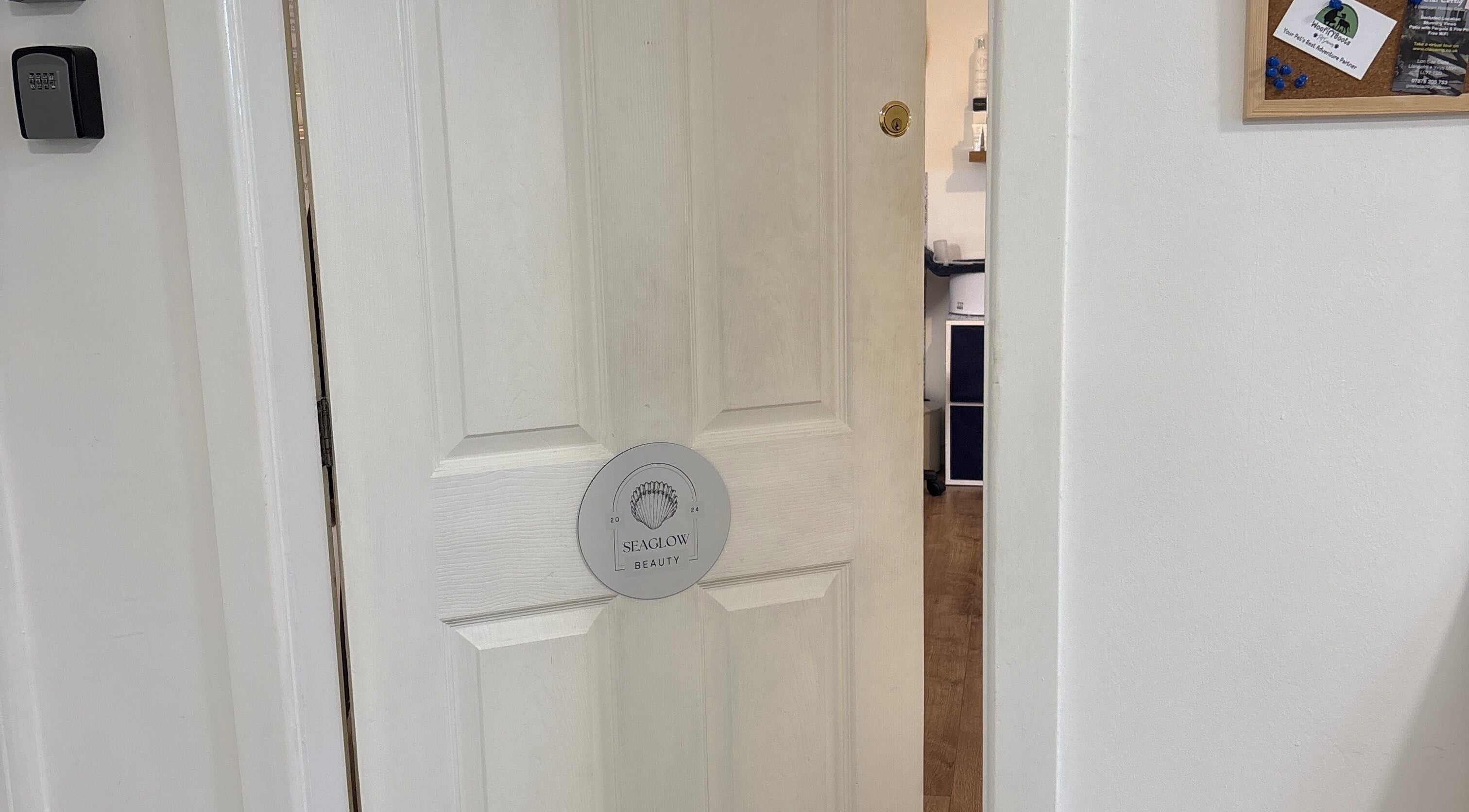 Entrance to Seaglow Beauty in Menai Bridge, Wales, GB featuring a partially open door with signage.