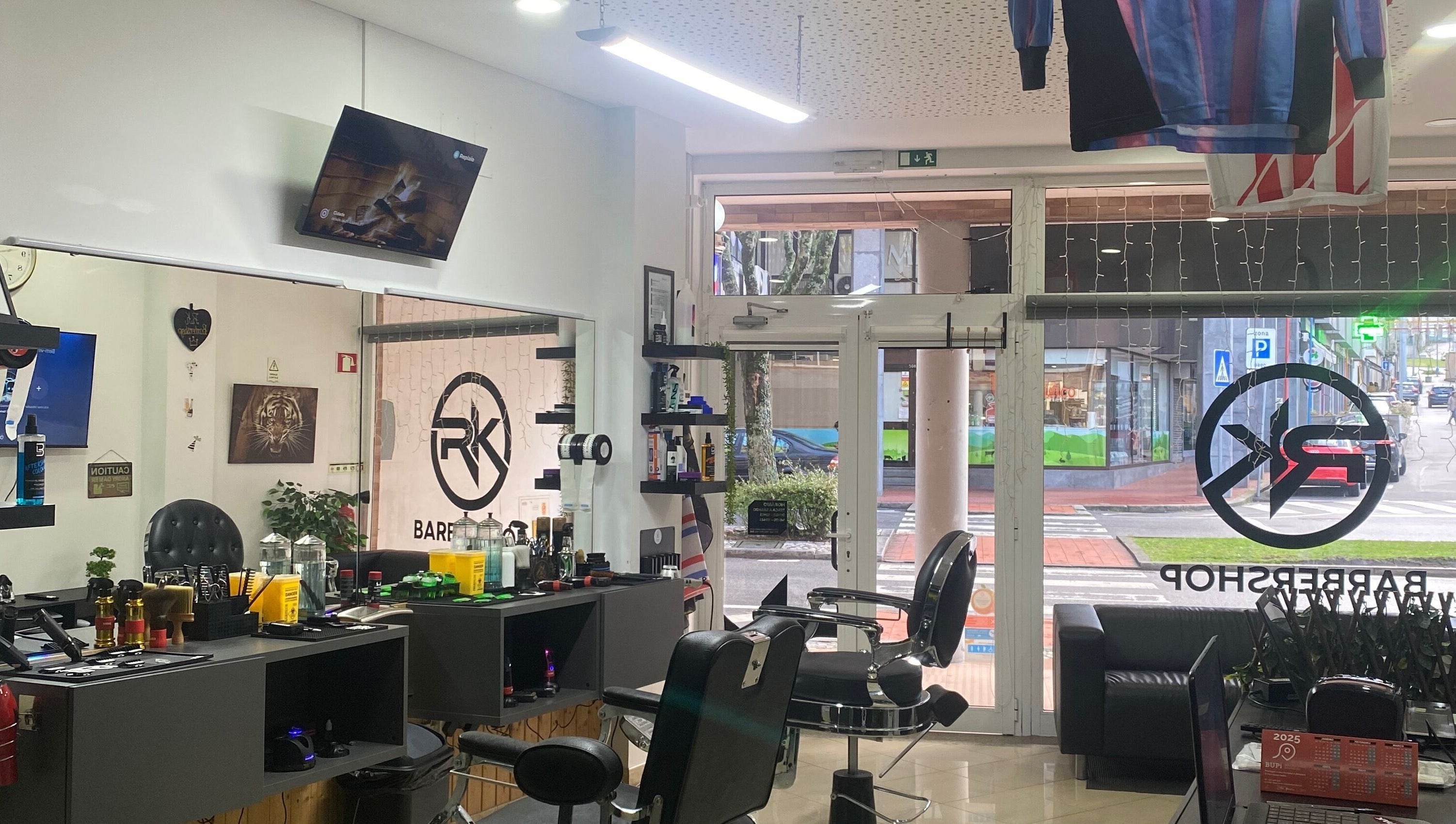 Interior moderno do Rkbarbershop em Vale De Cambra, Aveiro, PT, mostrando cadeiras e espelhos elegantes.