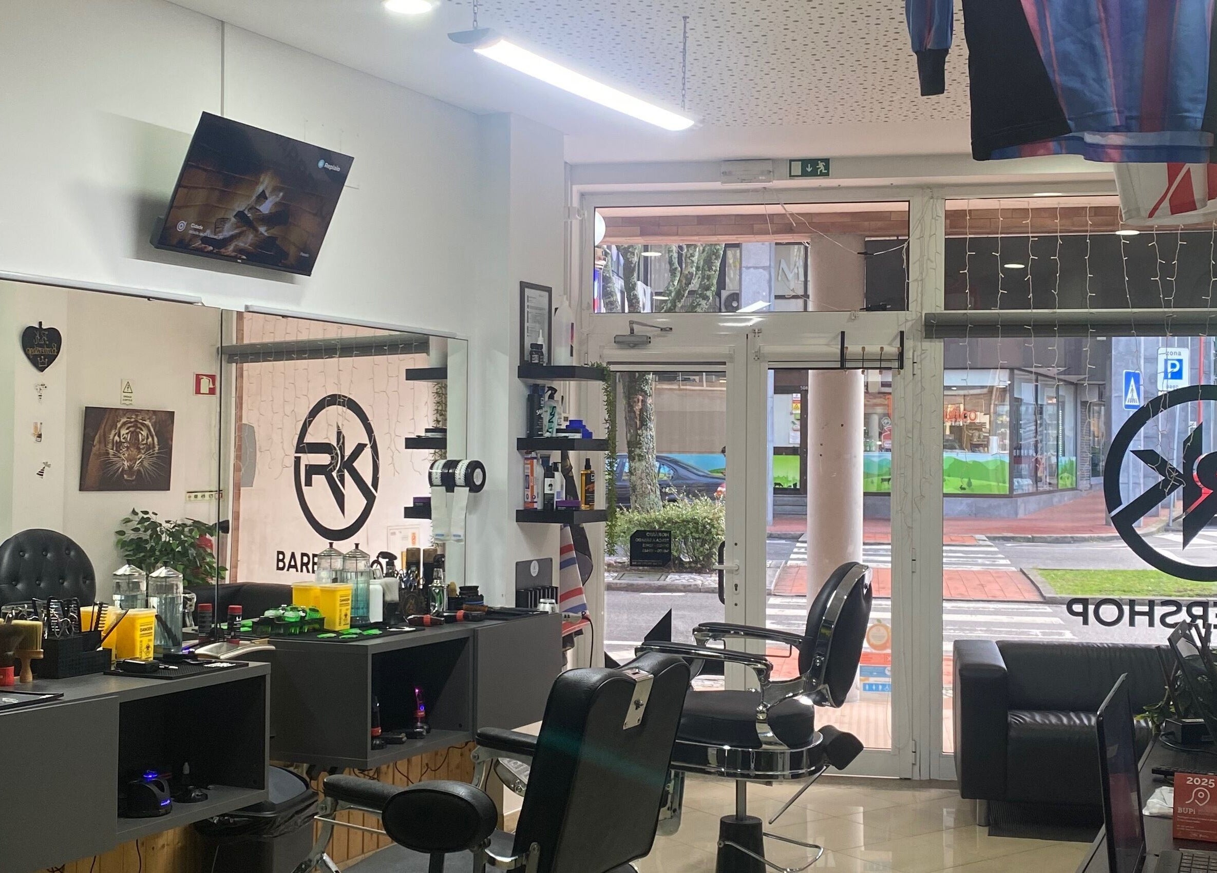 Interior moderno do Rkbarbershop em Vale De Cambra, Aveiro, PT, mostrando cadeiras e espelhos elegantes.