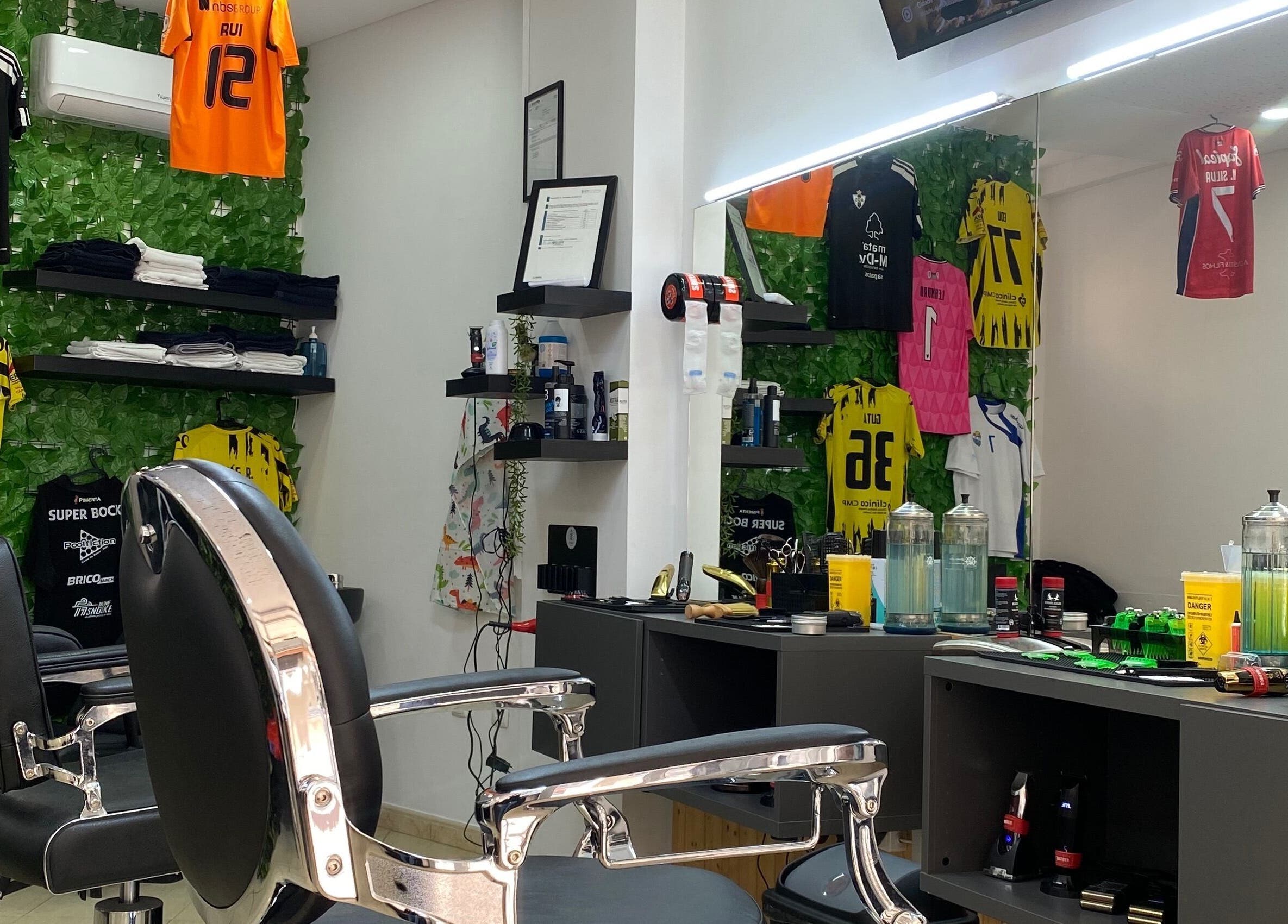 Interior moderno da Rkbarbershop em Vale De Cambra, Aveiro, PT com cadeiras de barbeiro e camisolas desportivas.