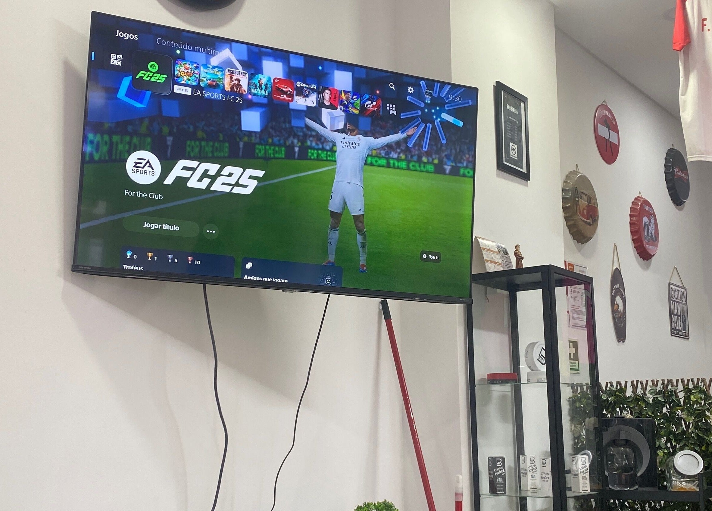 TV com jogo na parede da Rkbarbershop em Vale De Cambra, Aveiro, PT. Decoração temática esportiva ao redor.