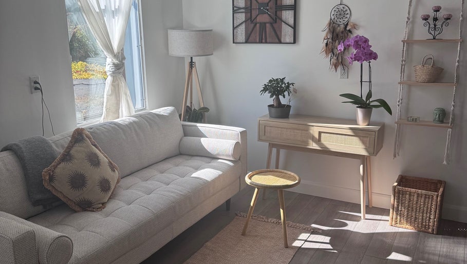 Sunlit boho-style lounge at Bien-être Boho NDG, Montréal, Québec, CA with couch, plants, and decorative elements.