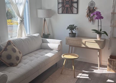 Sunlit boho-style lounge at Bien-être Boho NDG, Montréal, Québec, CA with couch, plants, and decorative elements.