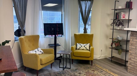 Comfortable seating area in Bien-être Boho NDG, Montréal, Québec, CA with yellow armchairs and a bookshelf.