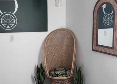 Cozy wicker chair at Bien-être Boho NDG, Montréal, Québec, CA, with a stylish mirror and plant decor.