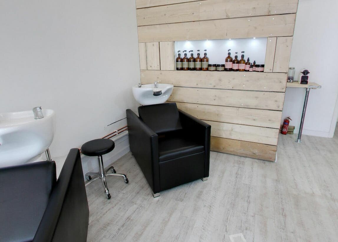 Bright salon interior at The Styling Rooms, Rugby, England, GB, featuring sleek chairs and wooden decor.