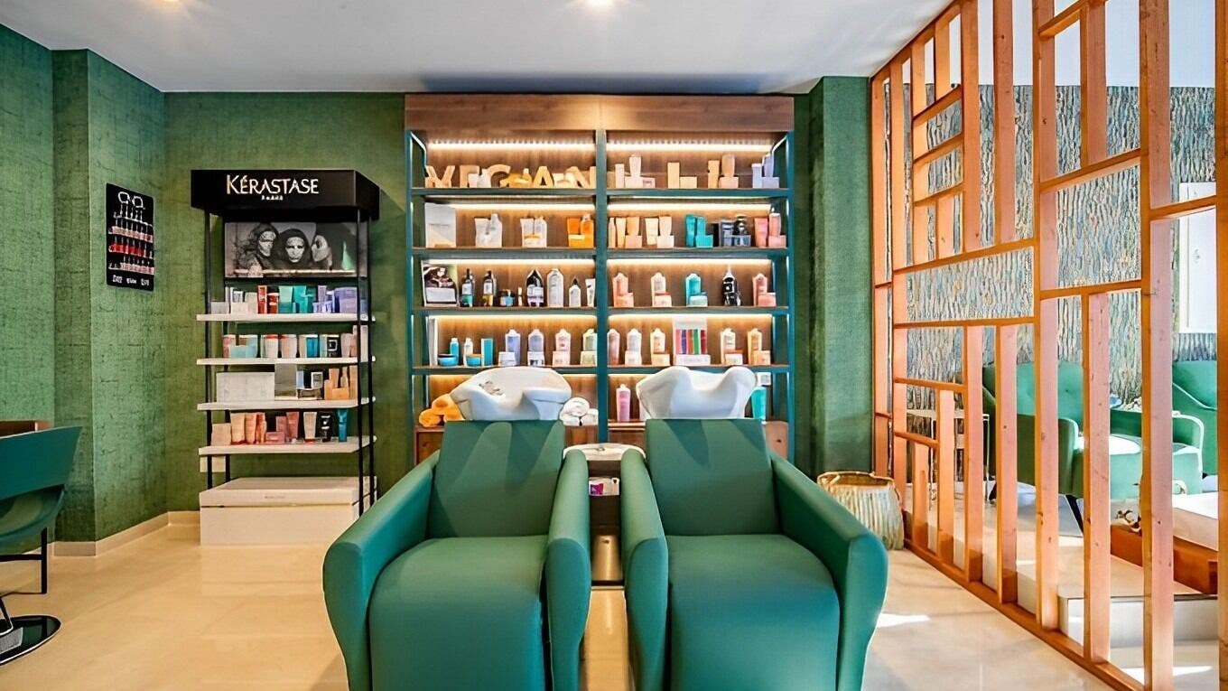 Interior de Mahra Experience en Marbella, Andalucía, ES con cómodas sillas y productos Kerastase en estantes.