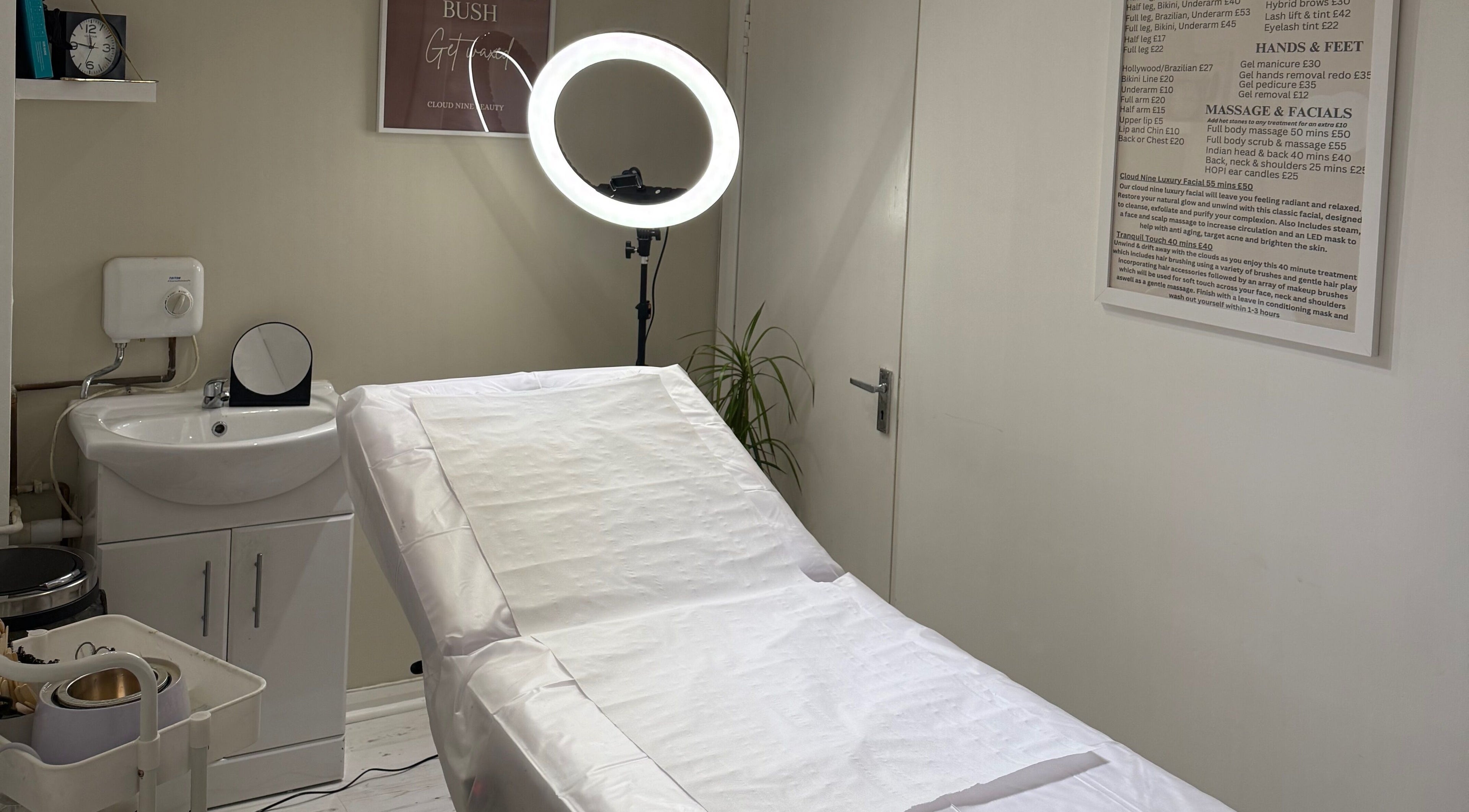 Treatment room at Cloud Nine Beauty in Deal, England, GB featuring a bed, sink, and illuminated mirror.