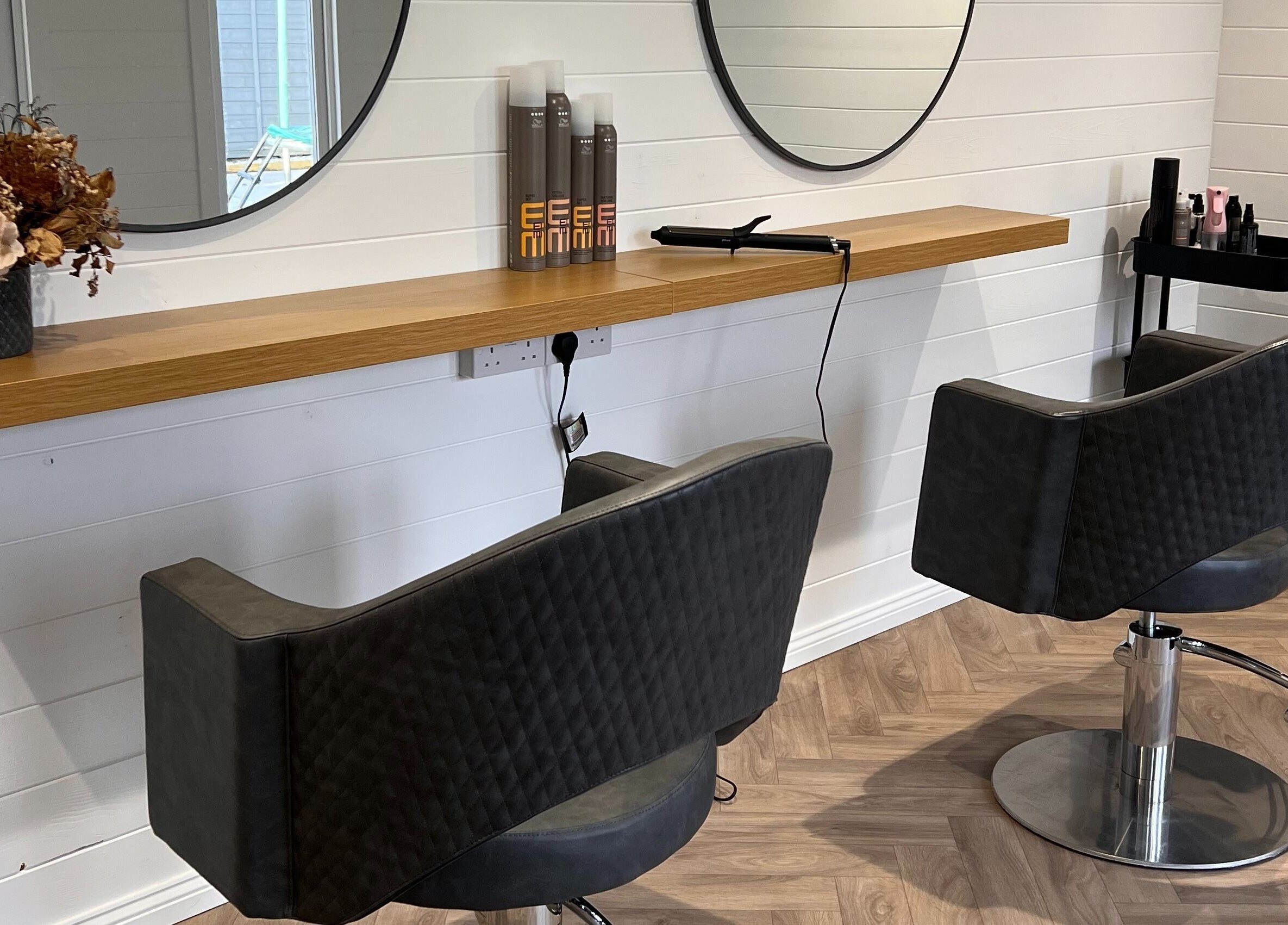 Modern salon station at Base Hair Studio, Llaneirwg, Cymru, GB with mirrors and styling chairs.