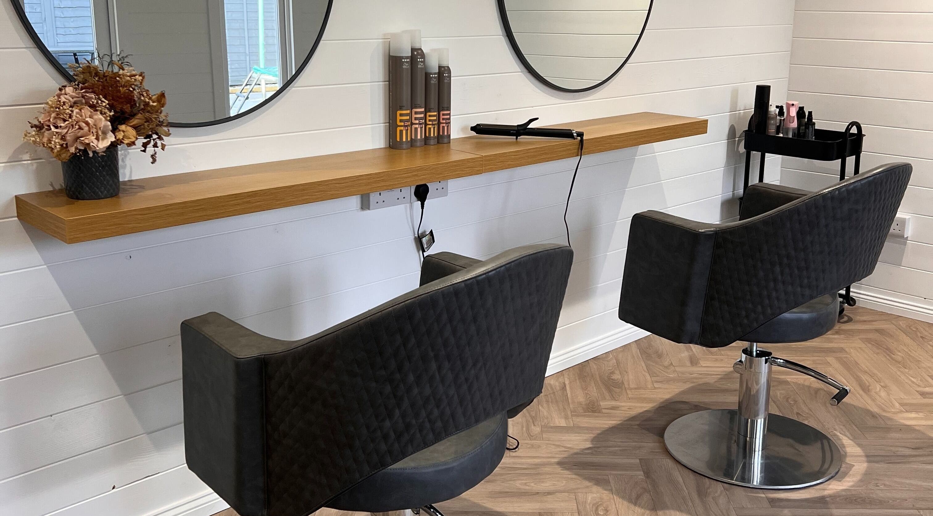 Modern salon station at Base Hair Studio, Llaneirwg, Cymru, GB with mirrors and styling chairs.