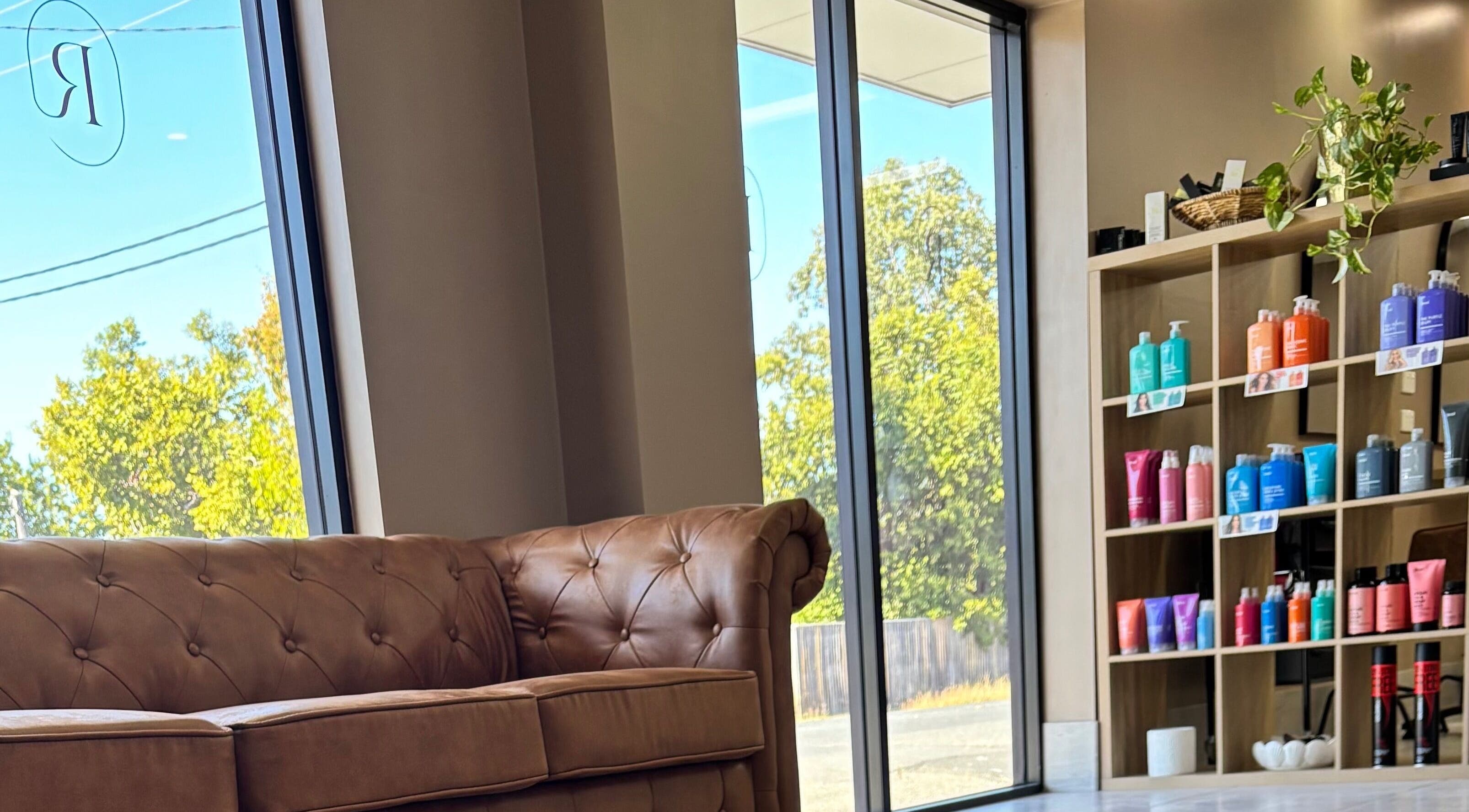Cozy waiting area at Revenge Hair and Body Salon, Berserker, Queensland, AU with plush sofa and product display.
