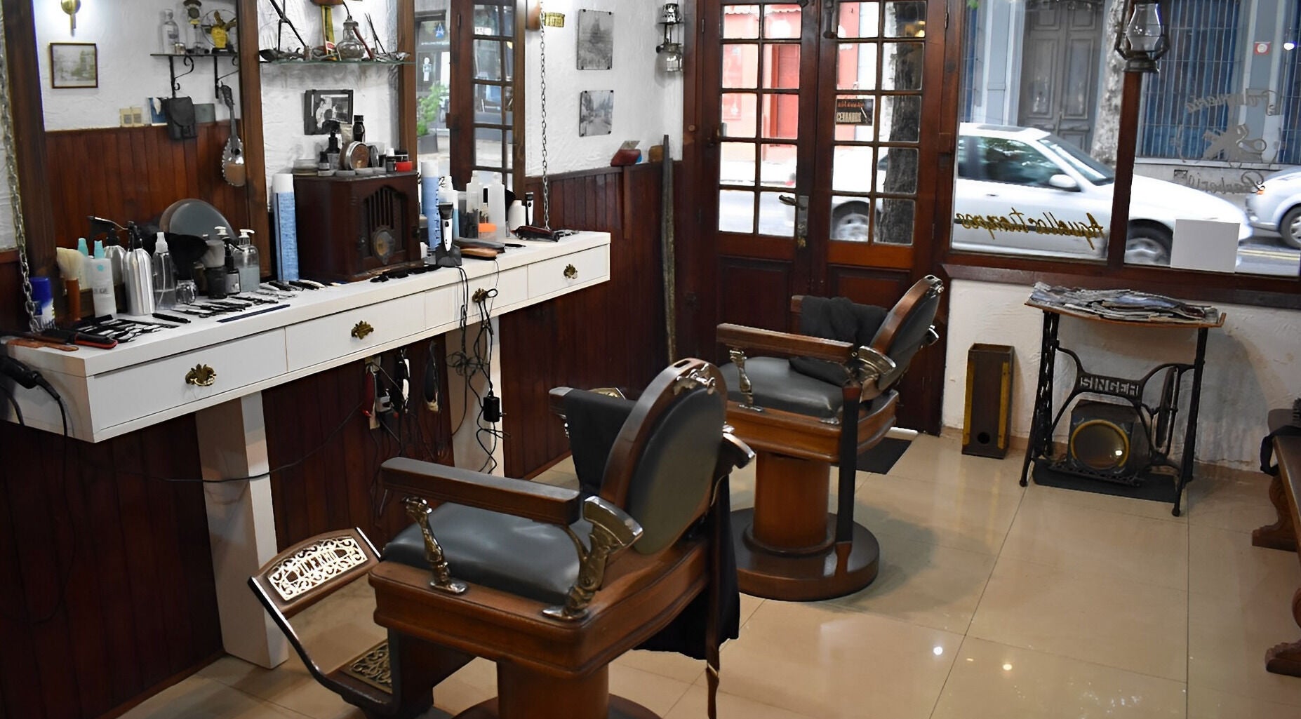 Interior de Peluquería & Barbería. Aquéllos Tiempos, Montevideo. Ambiente acogedor con sillas y espejos antiguos.