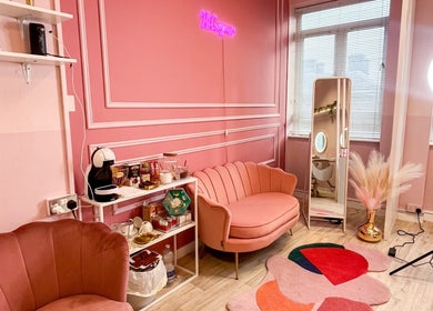 Chic pink interior of Lyn Beauty & Co., Dublin, County Dublin, IE, featuring stylish sofas and a neon sign.