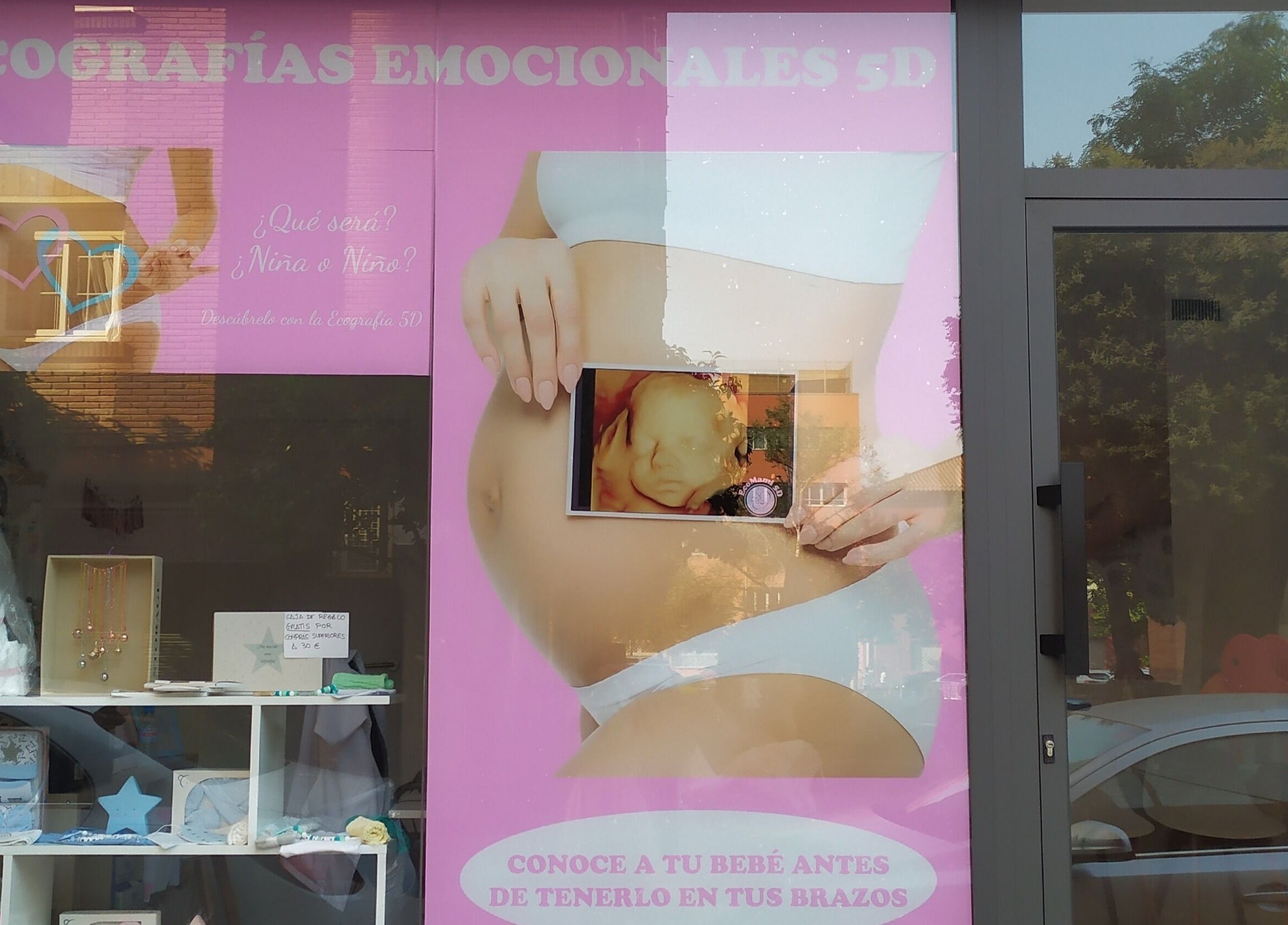 Fachada de EcoMami 5D en Gavà, Catalunya, ES, destacando ecografías emocionales en un vibrante cartel rosa.