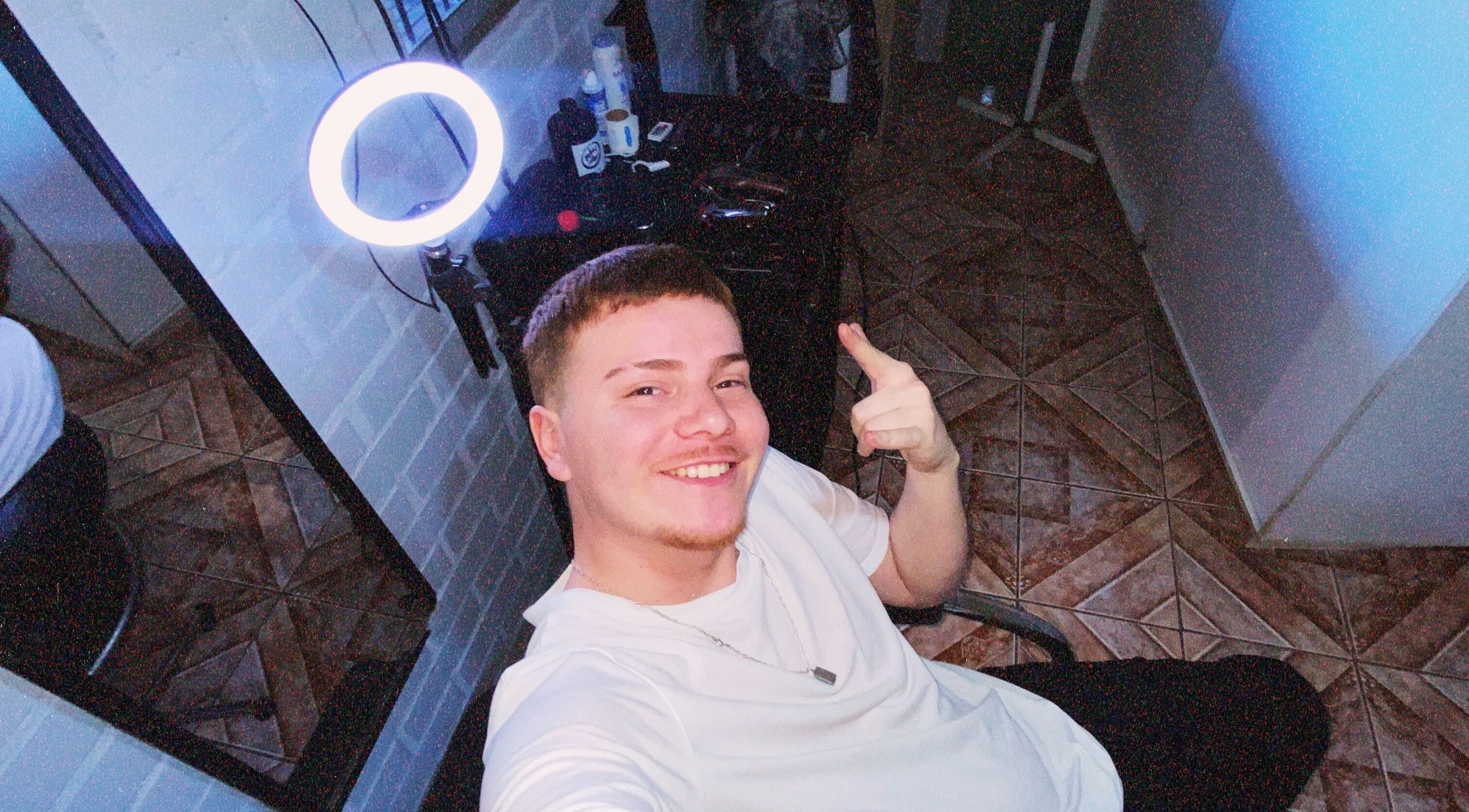 Cliente sonriente en Liberona Barber, Quilicura, Región Metropolitana, CL, frente a espejo iluminado.