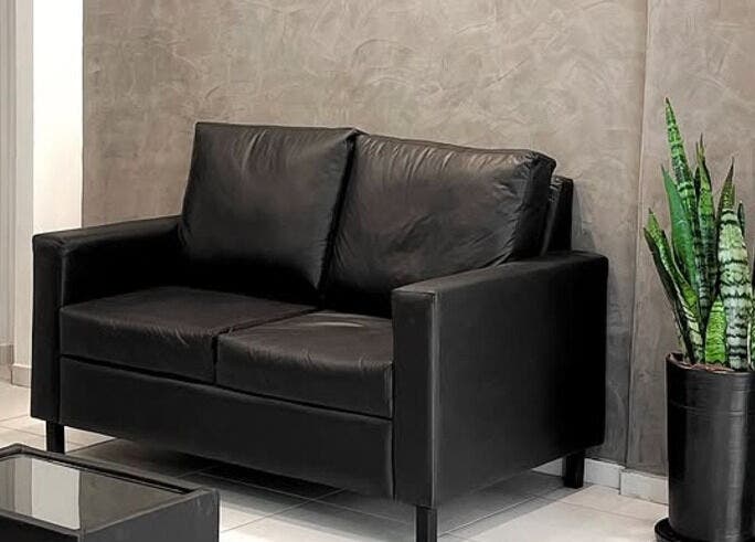 Acogedor rincón en Luca Salone, Asunción. Sofá negro y planta decorativa crean un ambiente tranquilo.