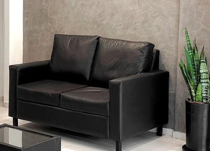 Acogedor rincón en Luca Salone, Asunción. Sofá negro y planta decorativa crean un ambiente tranquilo.