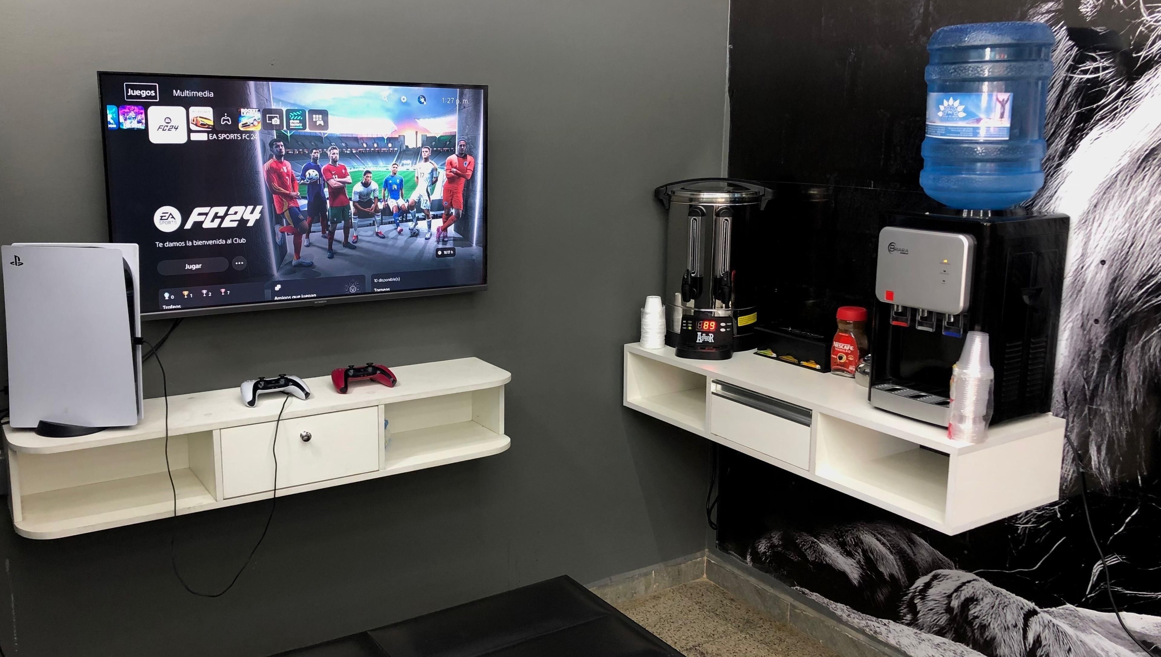 Sala de juegos en Blessed Barber Club Santos Doumont, 7mo Anillo, Santa Cruz, con consola PS5 y estación de bebidas.