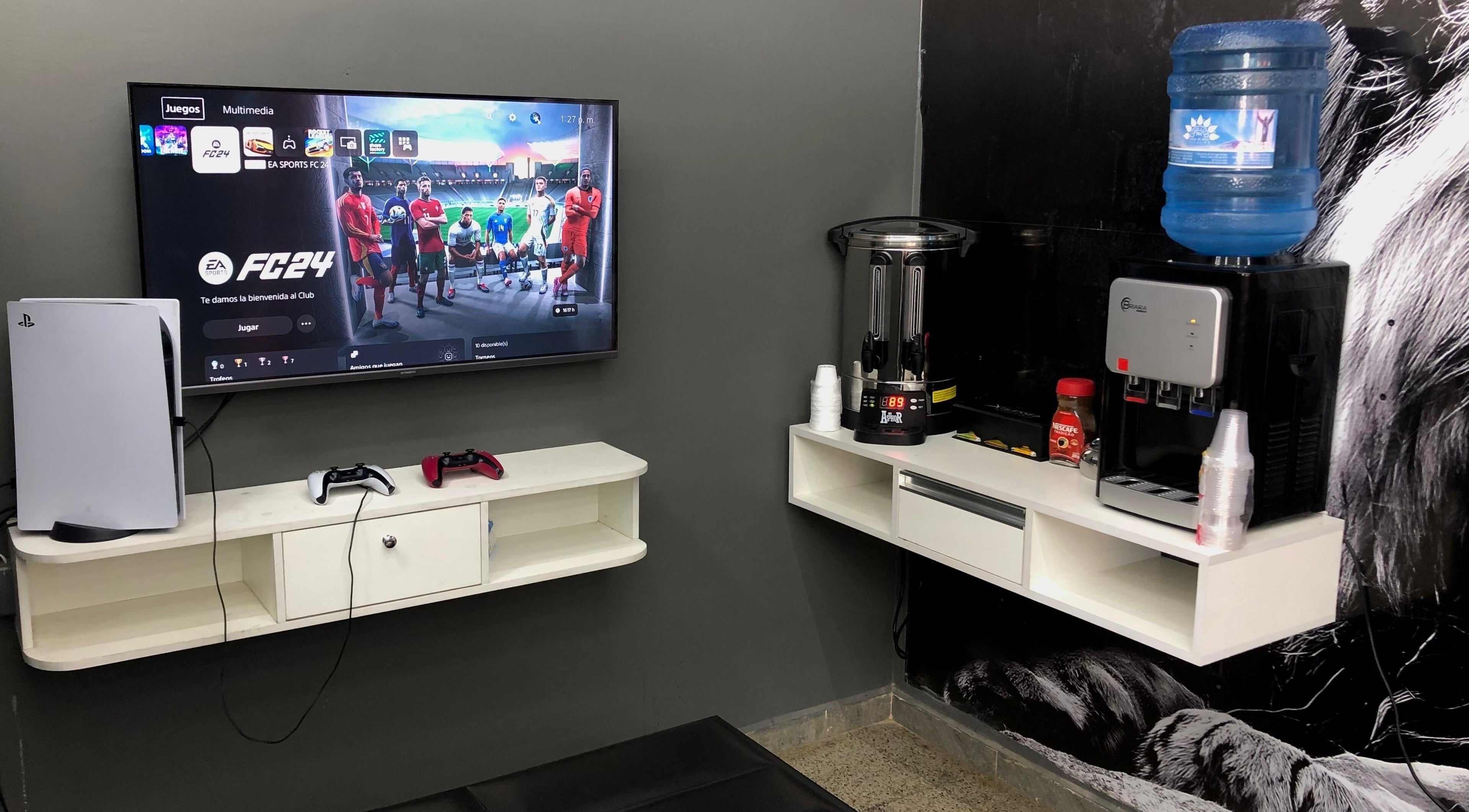 Sala de juegos en Blessed Barber Club Santos Doumont, 7mo Anillo, Santa Cruz, con consola PS5 y estación de bebidas.